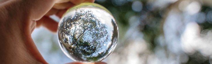 Eine Hand hält eine transparente Glaskugel ins Licht