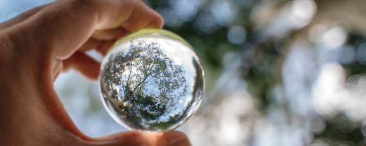 Eine Hand hält eine transparente Glaskugel ins Licht